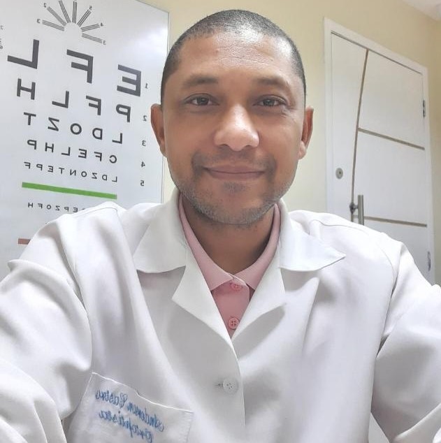 Anderson — Ortoptista do ISO, em jaleco branco diante de tabela optométrica